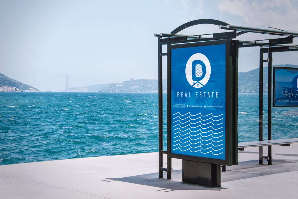 DB Real Estate city-light poster at a seaside bus stop
